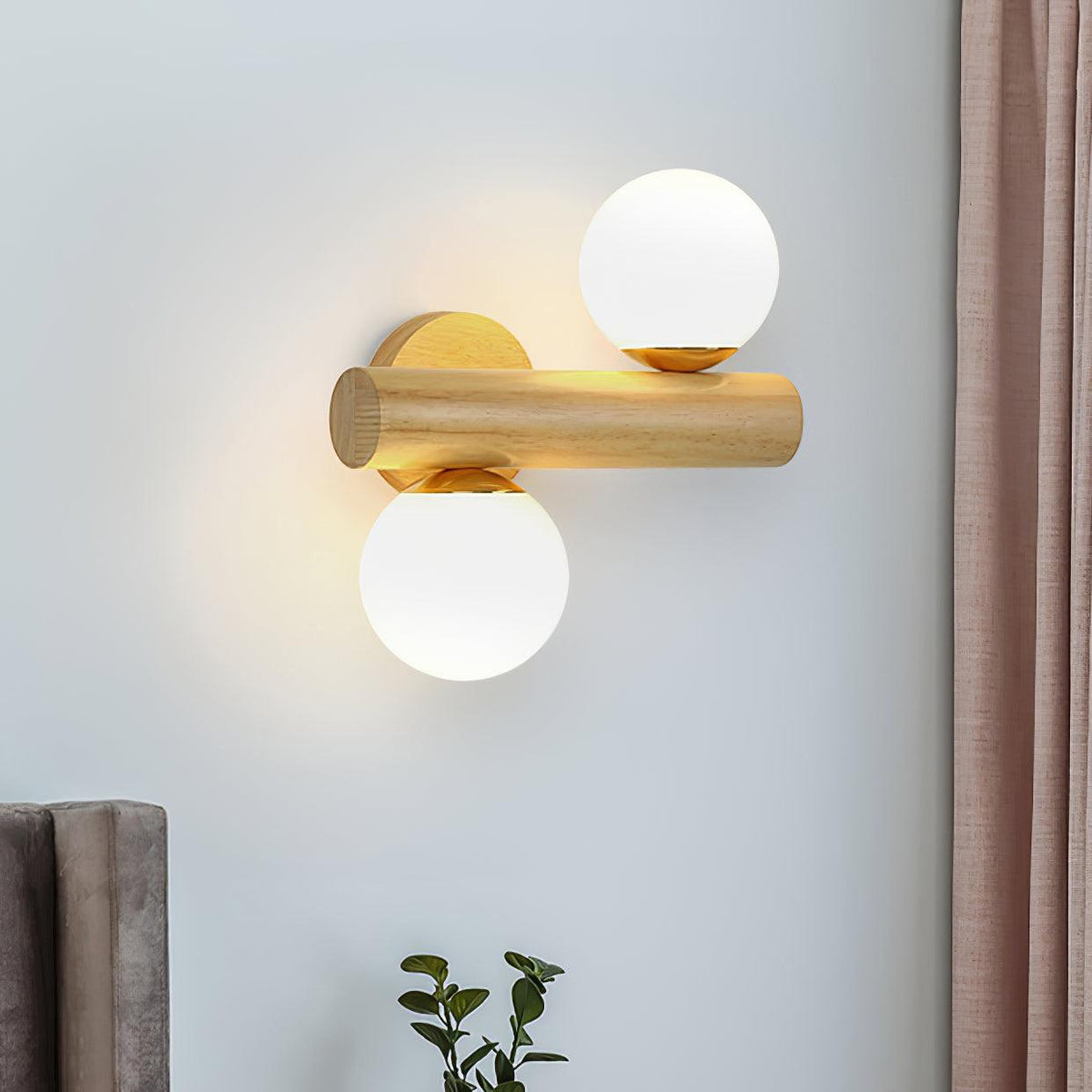 Wood rod of this Clérachic sconce turned horizontal, one globe above and one below, on a blue-grey wall beside a curtain.