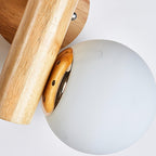 Close view of the gold-toned globe holder where a frosted glass globe meets the wooden rod on this Clérachic sconce.