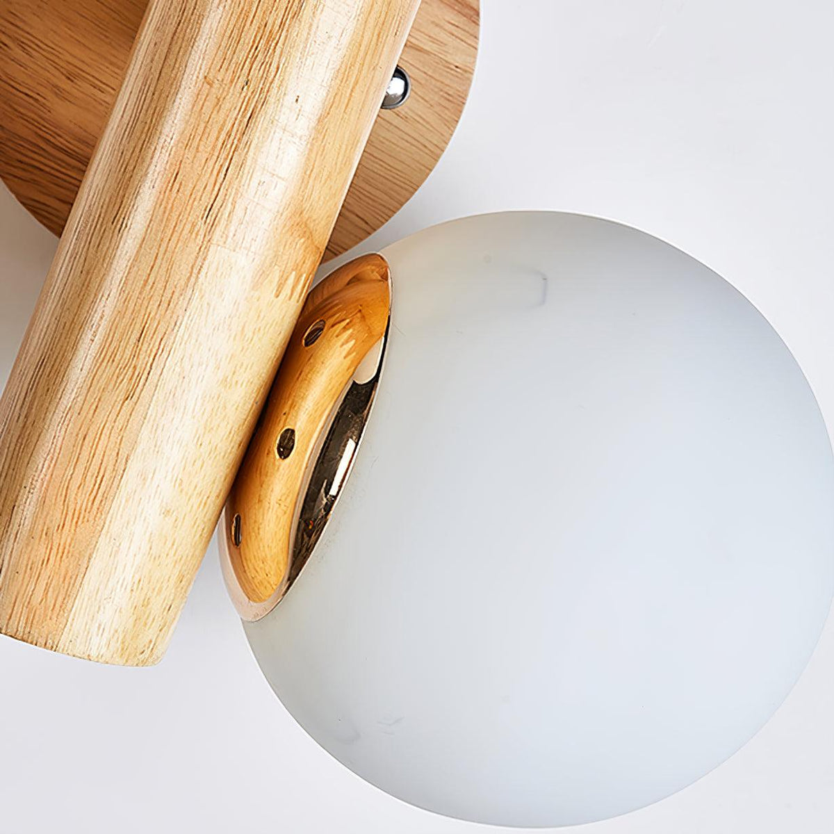 Close view of the gold-toned globe holder where a frosted glass globe meets the wooden rod on this Clérachic sconce.
