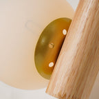 Close view of the round gold-toned fitting with its small holes joining the wooden rod to the globe on this Clérachic sconce.