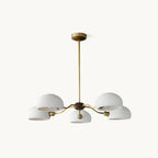 White ceramic dome shades on curved brass arms around a walnut hub, this Clérachic chandelier on a white backdrop.