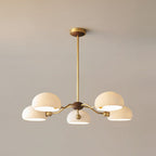 The five-light version of this Clérachic chandelier, its white shades lit from inside on a warm grey wall.