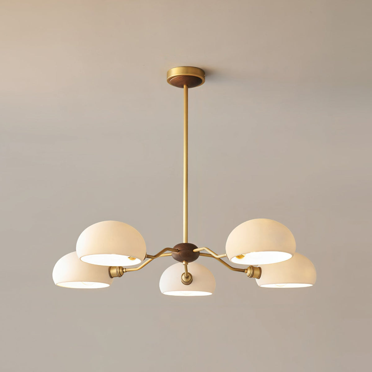 The five-light version of this Clérachic chandelier, its white shades lit from inside on a warm grey wall.