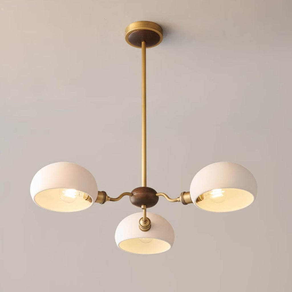 Close view of the three-light Clérachic chandelier: warm bulbs glow inside white shades around a walnut hub.