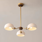 Close view of the three-light Clérachic chandelier: warm bulbs glow inside white shades around a walnut hub.