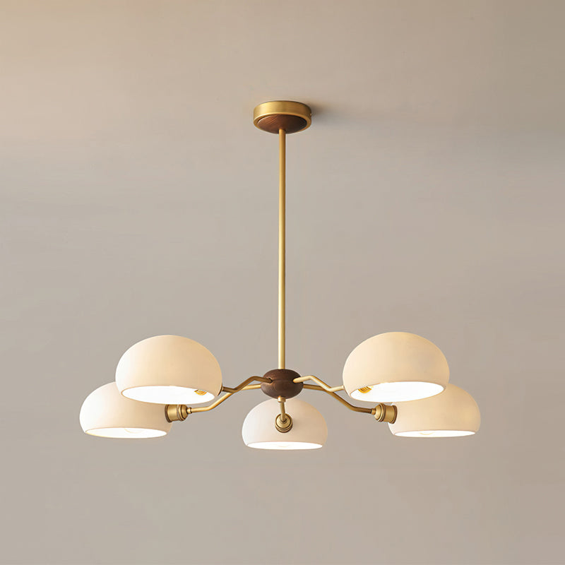Warm light inside the five white shades of this Clérachic chandelier, shown against a soft beige wall.