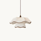 This Clérachic pendant on a plain white backdrop, with a two-tier pleated white shade, scalloped dark-brown trim and a thin brown cord.