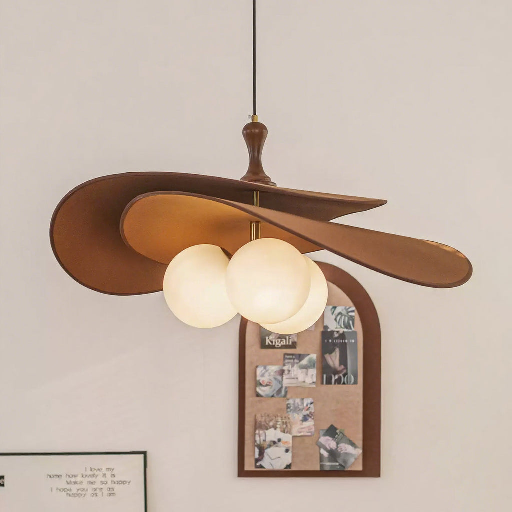 Brown version of this Clérachic pendant glowing beside an arched cork pinboard on a pale wall, its three opal globes lit under the shade.