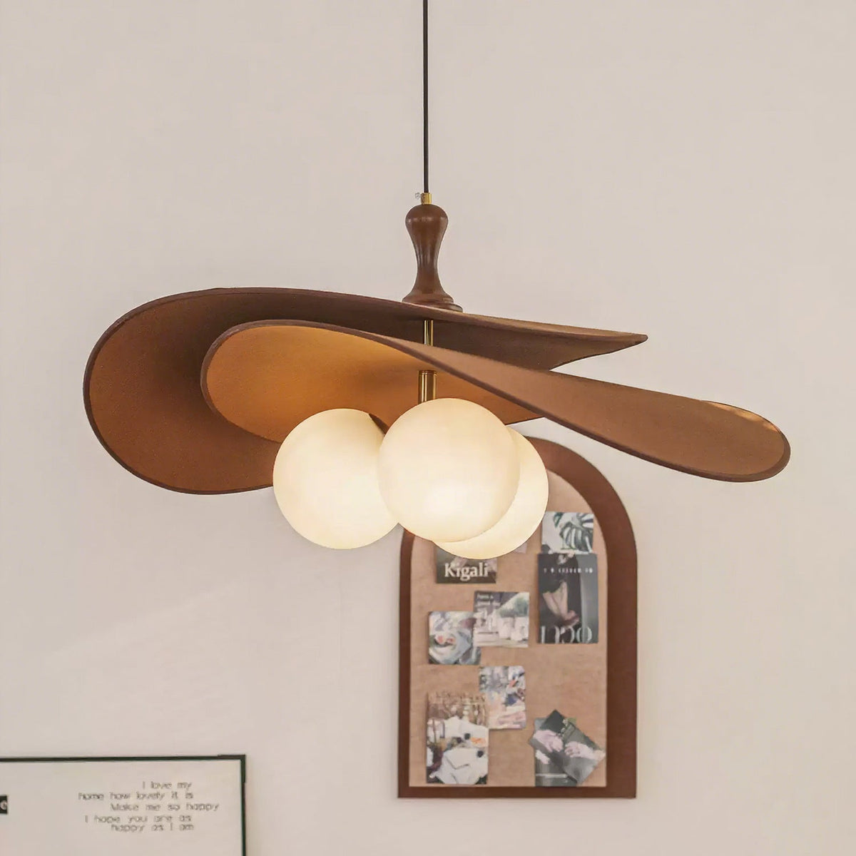 Brown version of this Clérachic pendant glowing beside an arched cork pinboard on a pale wall, its three opal globes lit under the shade.