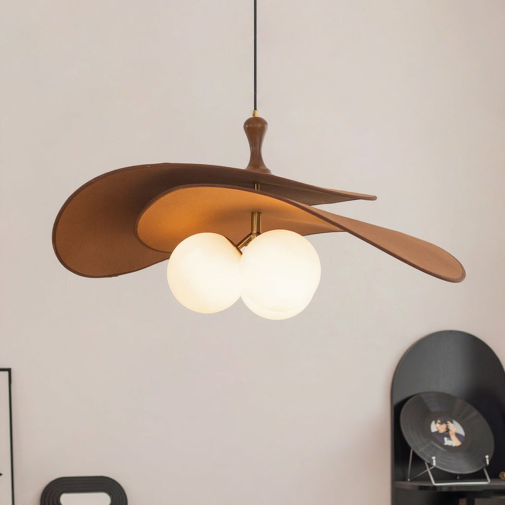 Close, angled view of this Clérachic pendant in brown, showing the wavy double shade and two lit opal globes against a pale wall.