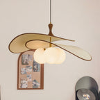 Wide view of the beige Clérachic pendant, with its turned wood stem and cluster of opal globes, beside an arched cork pinboard.