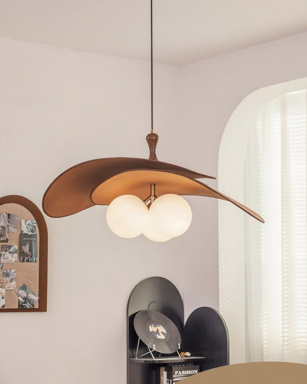 Brown Clérachic pendant seen from further back, hung near an arched pinboard and a curtained window with a black shelf below.