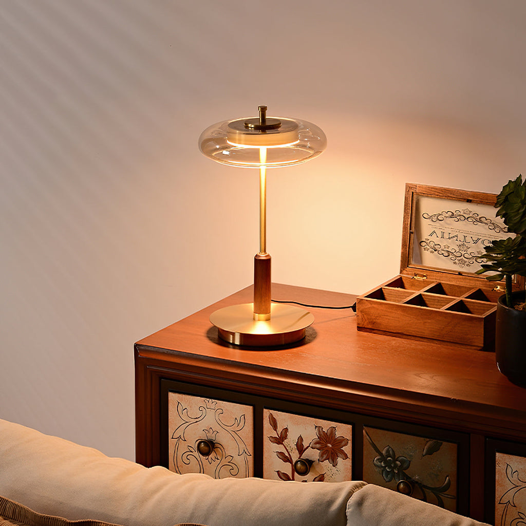 This Clérachic lamp lit on a painted wooden chest of drawers, warm light pooling on the brass base and a small wooden box.
