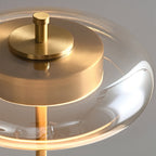Close view of the clear glass shade and brushed brass cap on this Clérachic lamp, with the warm ring of light beneath.