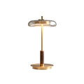 Unlit Clérachic table lamp against white, showing the glass dish shade, slim brass stem, walnut grip and flat round base.