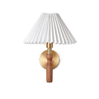 Studio view of this Clérachic wall light on white, with a wide pleated shade, brass collar and walnut handle.