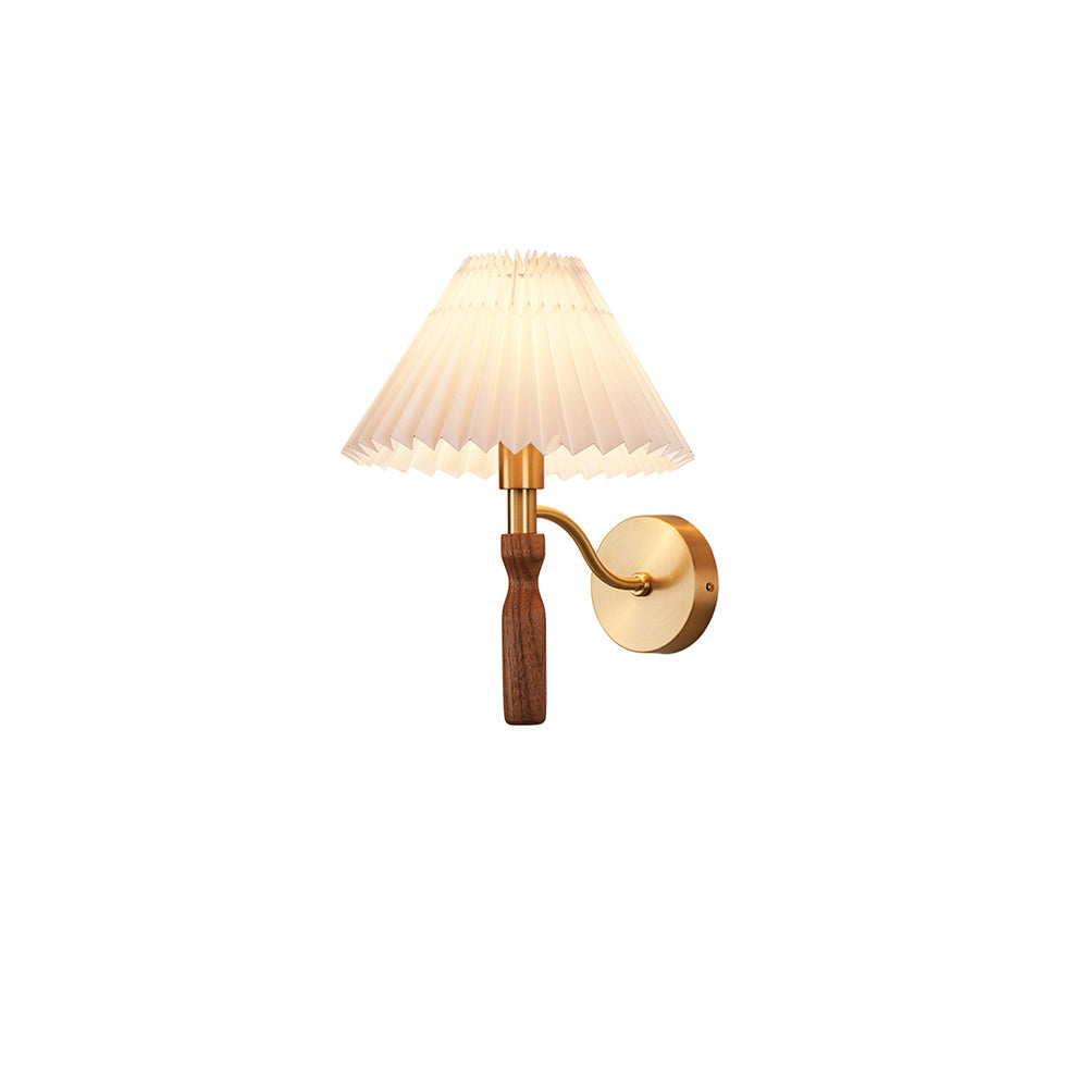 Small Clérachic wall light on a white backdrop, with a pleated shade and a curved brass arm to a walnut grip.