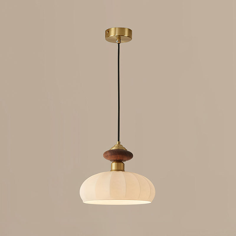 Unlit Clérachic pendant with a ribbed glass shade, walnut-coloured knob and brass canopy, on a warm taupe backdrop.