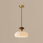 Unlit Clérachic pendant with a ribbed glass shade, walnut-coloured knob and brass canopy, on a warm taupe backdrop.