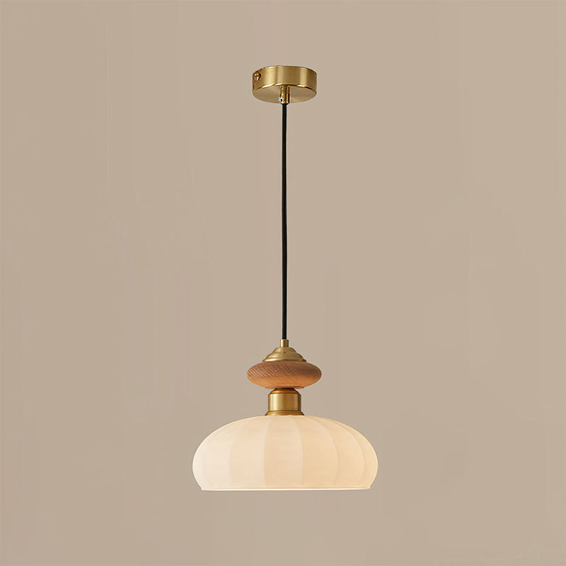 The same Clérachic pendant lit on a taupe backdrop, the ribbed glass shade glowing warm beneath the wooden and brass top.