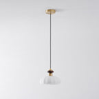Full-length view of this Clérachic pendant, from its brass ceiling plate and black cord to the ribbed white glass shade.