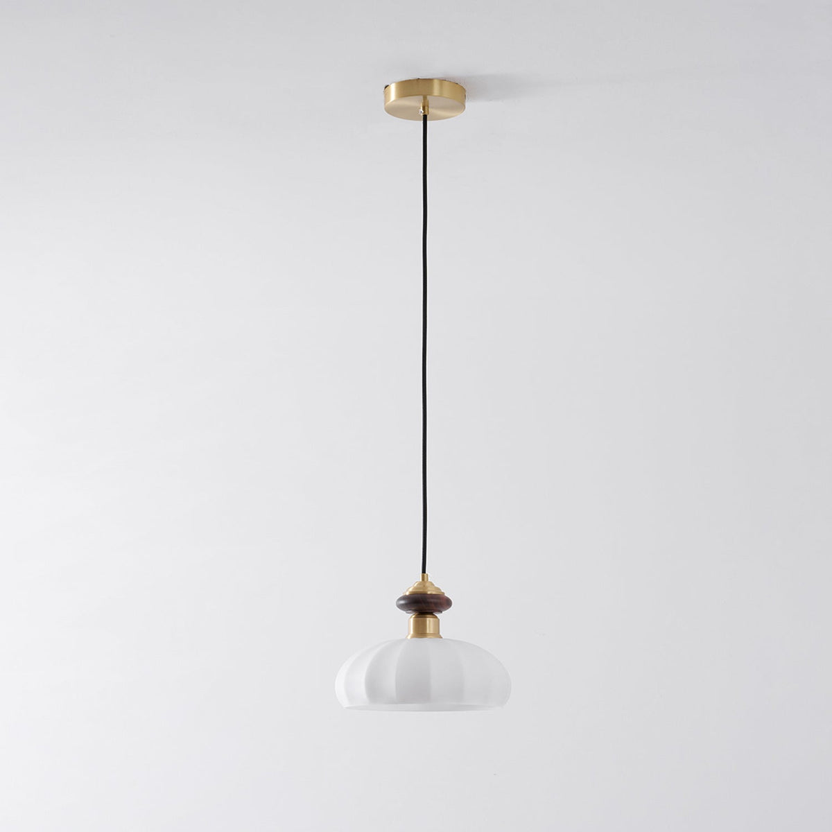 Full-length view of this Clérachic pendant, from its brass ceiling plate and black cord to the ribbed white glass shade.