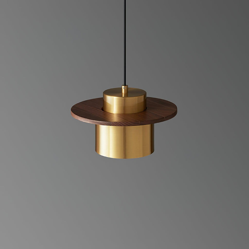 Brass cylinder shade under a round walnut brim on this Clérachic pendant, shown against a mid-grey backdrop.