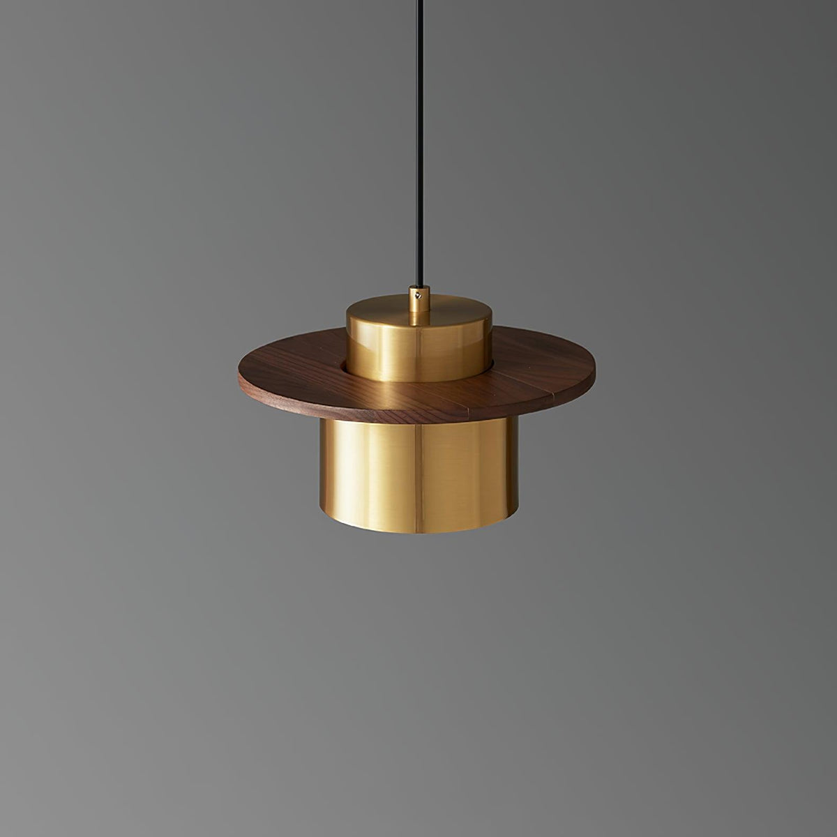 Brass cylinder shade under a round walnut brim on this Clérachic pendant, shown against a mid-grey backdrop.