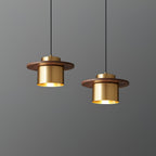 A pair of brass-and-walnut Clérachic pendants hang at different heights against a grey wall.