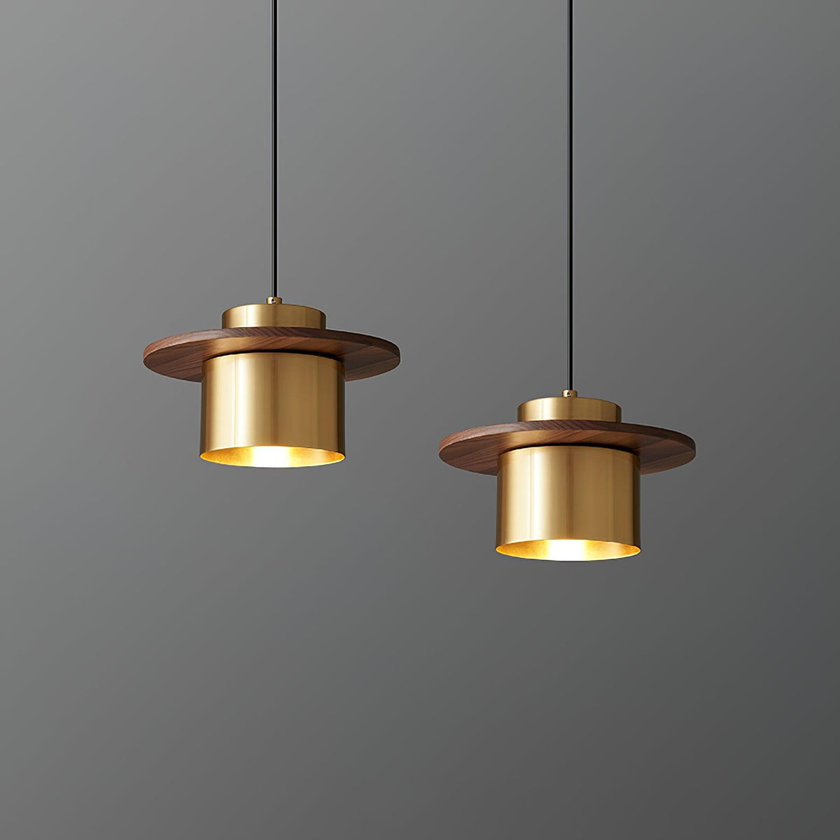 A pair of brass-and-walnut Clérachic pendants hang at different heights against a grey wall.