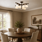 This Clérachic semi flush ceiling light hangs over a round dark wood table with cream chairs and a landscape painting.