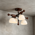 Close view of four frosted glass shades and the ball-ended walnut bars on this Clérachic semi flush light, on a grey wall.