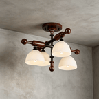 Close view of four frosted glass shades and the ball-ended walnut bars on this Clérachic semi flush light, on a grey wall.