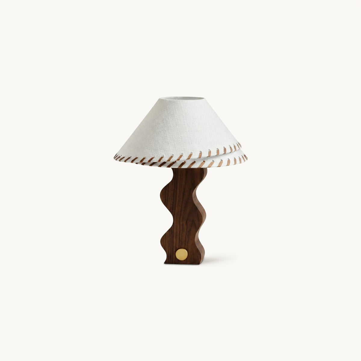 Walnut table lamp from Clérachic with a wavy sculpted base, a brass dial and a white linen shade stitched with leather lacing.