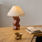 Table lamp from Clérachic on a herringbone oak desk, with an open book and a stoneware mug nearby.