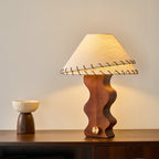 Lit Clérachic table lamp on a dark sideboard, its warm light falling on a small speckled bowl at the left.
