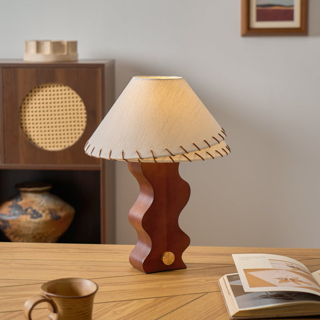Clérachic table lamp on a light oak desk in front of a walnut cabinet with a round rattan door and a glazed vase.