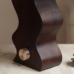 Close view of the dark walnut base of this Clérachic table lamp, with its ribbed brass dial on the curved side.