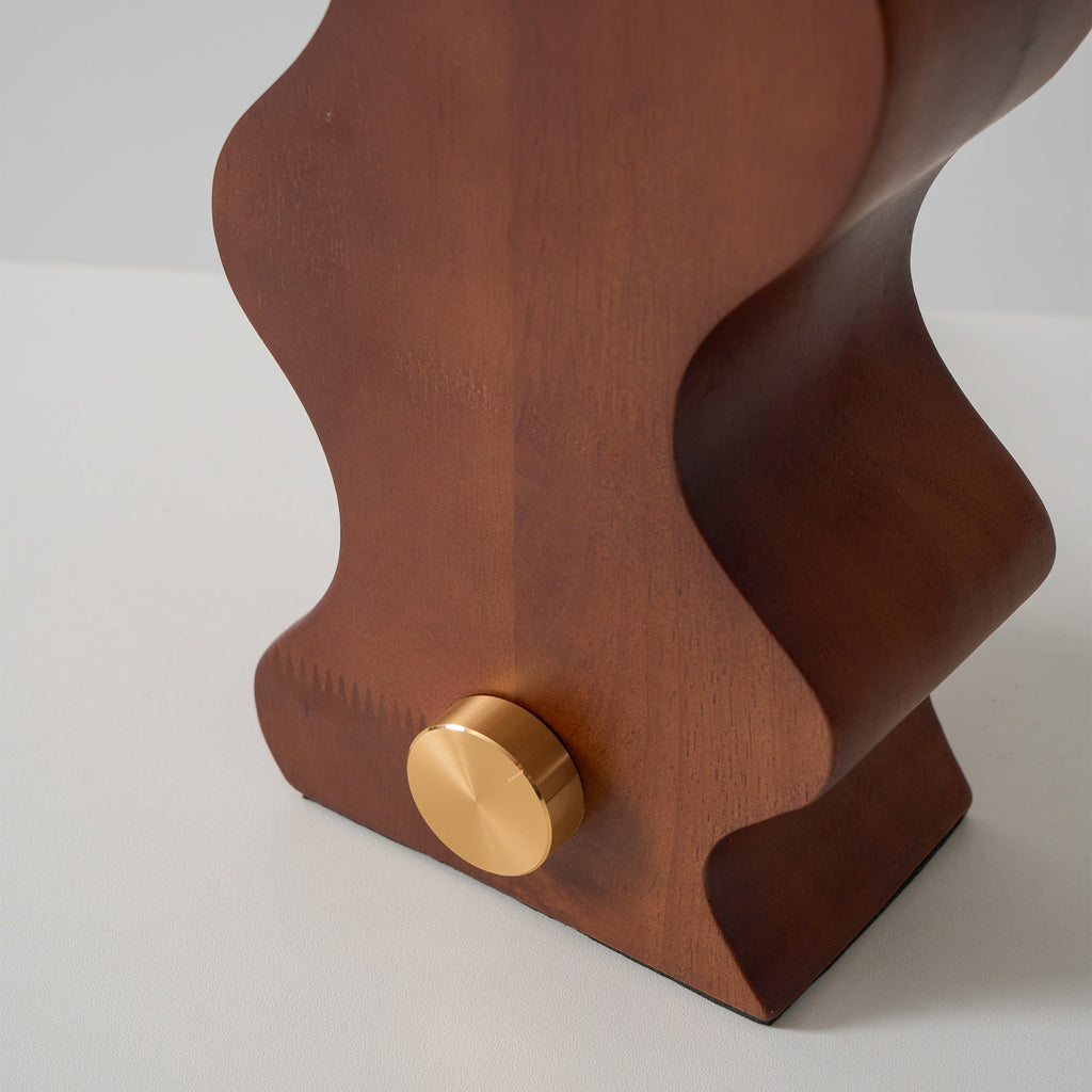 Close view of the grain on the walnut base of this Clérachic table lamp, with its round brass dial on the side.