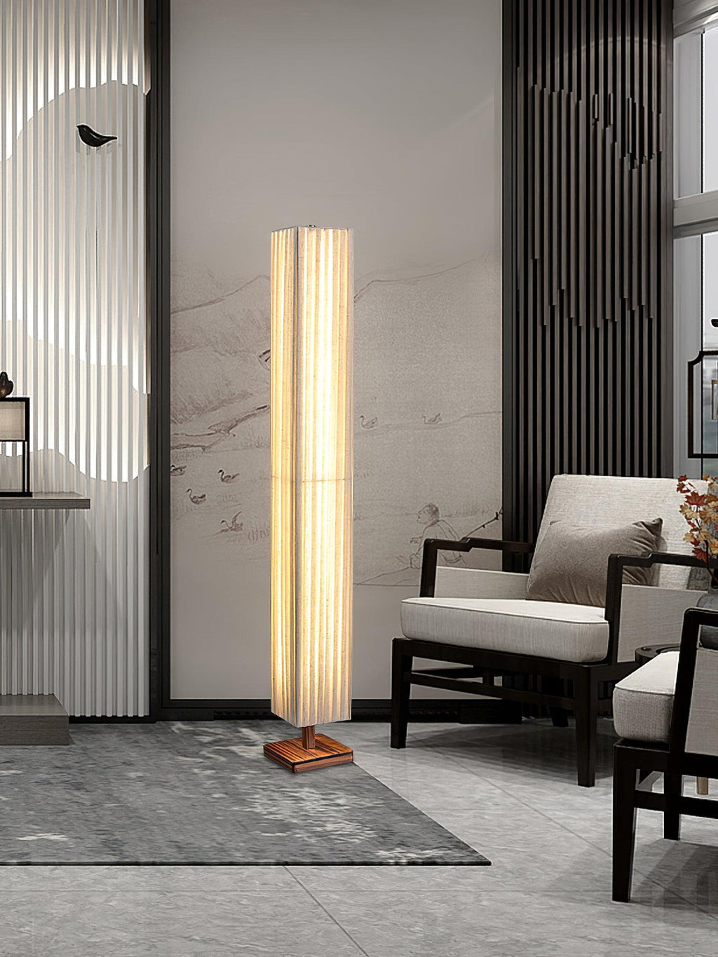 Clérachic floor lamp standing in a tall grey-and-white living room, beside a black-framed chair and a grey rug.