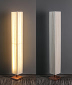 Two views of the Clérachic floor lamp side by side, one lit from the front and one showing the plain pleated side.