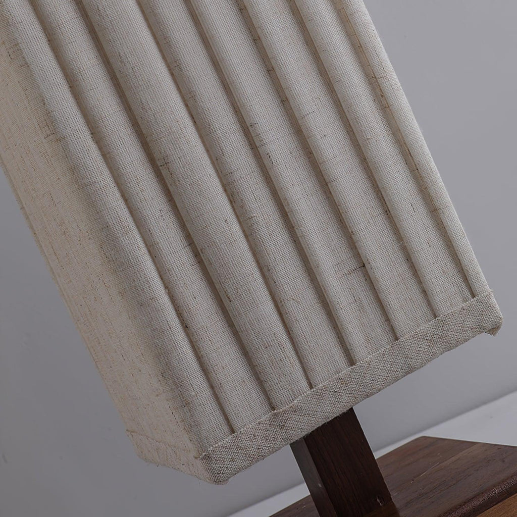 Close view of the linen-textured pleats and stitched hem of this Clérachic floor lamp shade, above its wooden base.