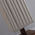 Close view of the linen-textured pleats and stitched hem of this Clérachic floor lamp shade, above its wooden base.