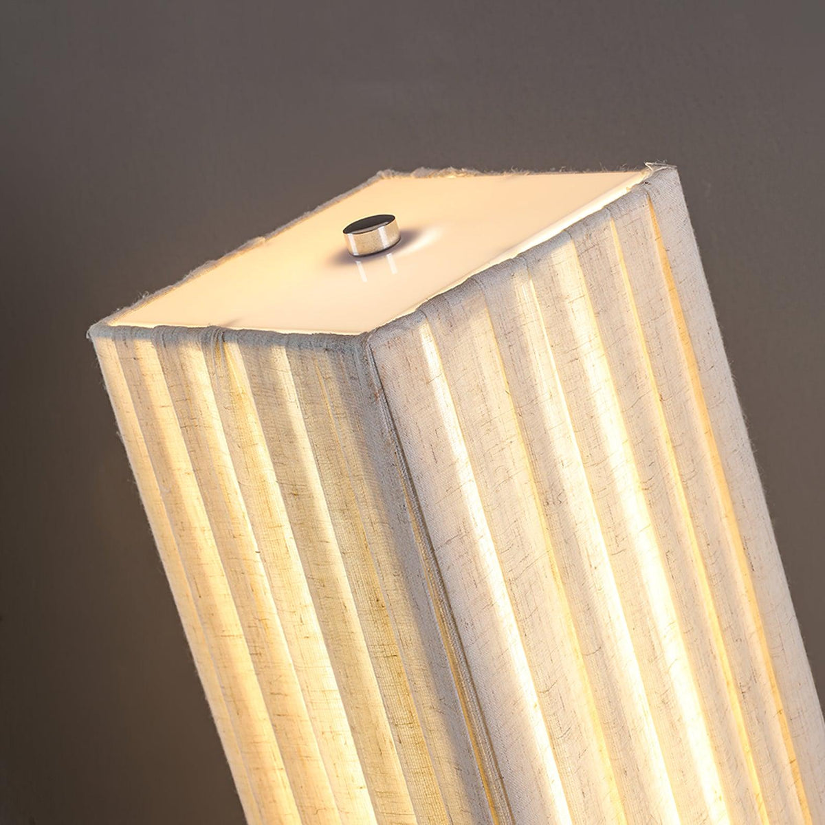 Looking down on the top of this Clérachic floor lamp, with the pleated shade glowing and a small metal cap on top.