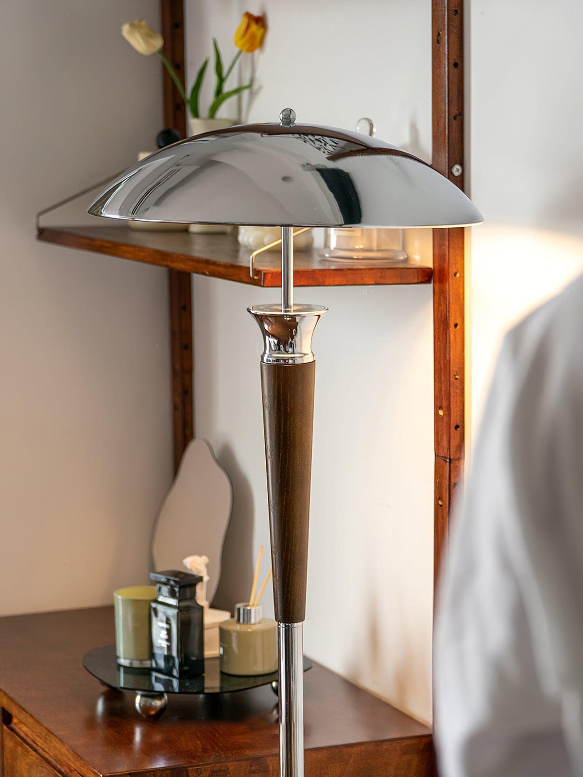 Close view of the chrome dome shade and walnut tapered stem of this Clérachic floor lamp, beside a wooden shelf and candles.