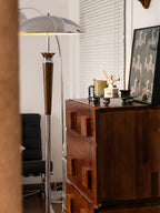 Lit Clérachic floor lamp with a chrome dome and walnut stem stands behind a dark wood chest, with a zebra-print wall hanging.