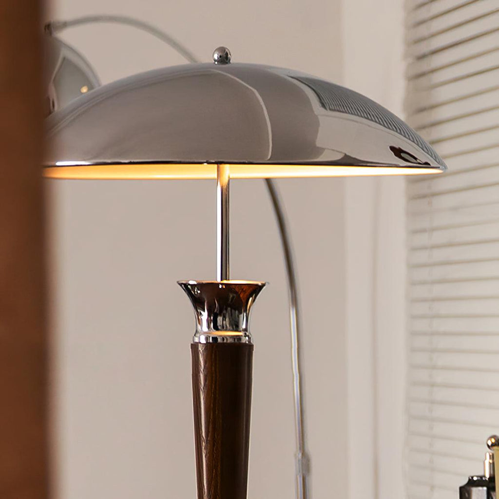 Close view of the underside of the chrome dome shade on this Clérachic floor lamp, lit warm, with a walnut stem below.
