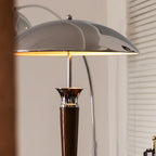 Close view of the underside of the chrome dome shade on this Clérachic floor lamp, lit warm, with a walnut stem below.