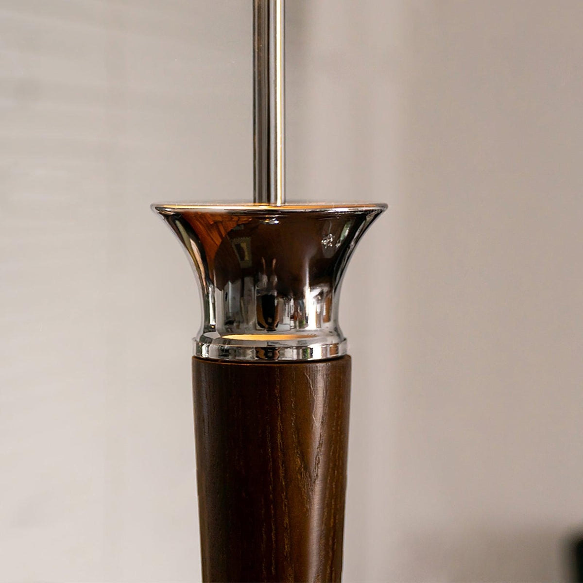 Close view of the flared chrome collar where the walnut stem of this Clérachic floor lamp meets the slim chrome pole.