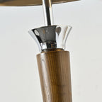 Close view of the walnut stem and flared chrome collar on this Clérachic floor lamp, against a plain pale backdrop.